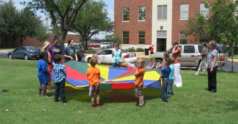 Human Services students playing parachute with kids