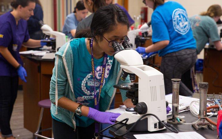 Photo of HSU student looking through microscope in laboratory.